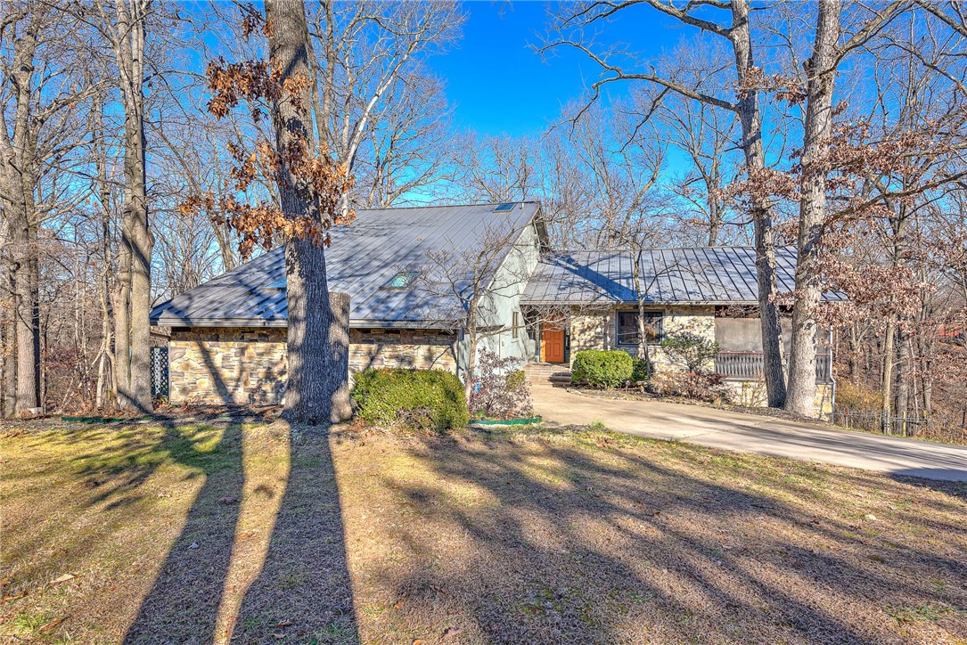 Discover the perfect blend of nature and convenience in this charming home nestled on two lots, totaling 4.41 acres of wooded serenity. Only 1.2 miles to Downtown Rogers and .3 miles to Lake Atalanta. Remodeled luxurious primary suite with spa bathroom and spacious closet with custom built-ins. Indulge in outdoor living on the grand screened-in patio accessible from the primary suite and the living room. Upper level has guest en-suite. Lower lever has versatile space with bedroom, game room and office. Embrace outdoor living with the included storage building and greenhouse, completing this unique property that harmonizes modern comfort and natural beauty.