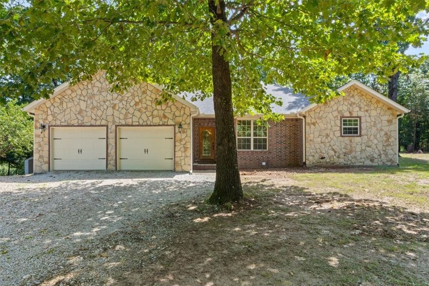 This custom-built country home blends comfort, functionality, and modern upgrades on a flat, park-like 1-acre lot. Built in 2007, the single-story, 2,692 sq ft home features 4 bedrooms, 2.5 baths, and an open floor plan with a spacious kitchen, stainless steel appliances, island, pantry, and dining area. A wood-burning stove—capable of heating the entire home—adds warmth and charm. The exterior features brick-and-stone construction, mature shade trees, a garden area, and a new wooden back deck wired for a hot tub—perfect for entertaining. A spacious attached garage adds extra storage and convenience. Located just a short distance from Hickory Creek Marina, this peaceful retreat is ideal for anyone seeking quiet, country living with modern amenities in the heart of Arkansas.