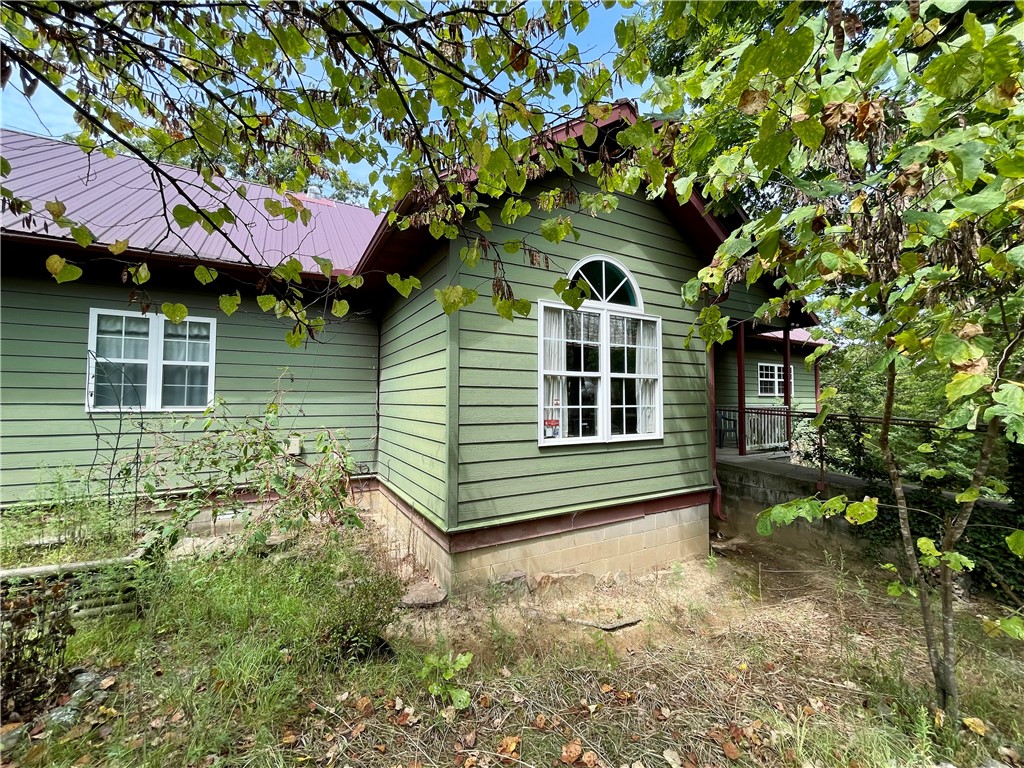 This custom home, built in 2006, is situated on 11.5 secluded wooded acres with a natural spring flows year round, offering views for miles from its back deck. The main floor comprises 3bed/2.5baths including one room currently used as an office with a half bath. A guest bedroom features its own private bath, while the primary bedroom boasts a jacuzzi bath, separate walk-in shower, and double vanity. A 492 sq ft basement includes 1bath & office/flex room.13x16 storm shelter used as bedroom.Steel fire door. A new generator providing emergency backup power. The property also features a 610 ft well with a new pump and tiles, a new double oven in the kitchen, a separate water heater for the kitchen, complemented by an 80-gallon water heater for the rest of the home. A 12x12 storage building and Ozarks Go Fiber Optic internet and cable services available. With its serene and private setting, this home offers an ideal escape, located 15-20 minute drive from Huntsville or Elkins, AR with easy access to all of NW AR.