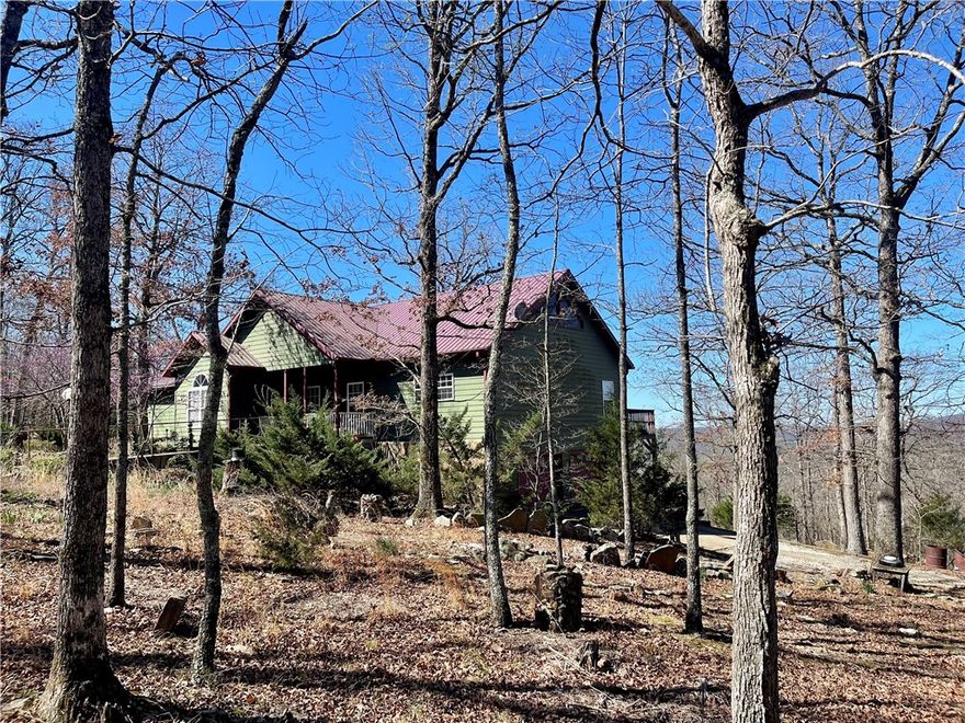 11.5 acres in the beautiful Ozarks! This custom home, built in 2006, situated on secluded wooded acres with a natural spring flows year round, offering views for miles from its back deck. The main floor comprises 3bed/2.5baths including one room currently used as an office with a half bath. A guest bedroom features its own private bath, while the primary bedroom boasts a jacuzzi bath, separate walk-in shower, and double vanity. A 492 sq ft basement includes 1bath & office/flex room.13x16 storm shelter used as bedroom.Steel fire door. A new generator providing emergency backup power. The property also features a 610 ft well with a new pump and tiles, a new double oven in the kitchen, a separate water heater for the kitchen, complemented by an 80-gallon water heater for the rest of the home. A 12x12 storage building and Ozarks Go Fiber Optic internet and cable services available. Approx 35-40 min commute to Fayetteville & Springdale, AR.