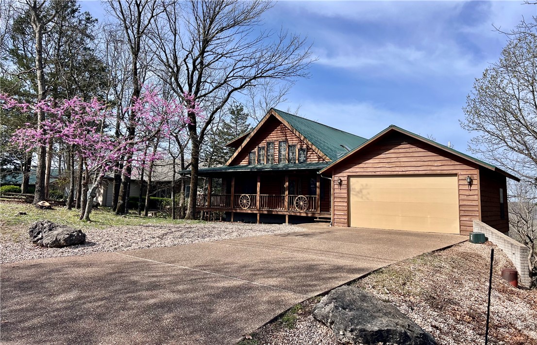Cozy log cabin home with beautiful views of Table Rock Lake. This home features a 2 car garage, wrap around decks, double sided fireplace, sunroom, 2 living rooms, sitting area with built ins just outside the primary suite, new HVAC system in Feb. 2025. Holiday Island assessment fees due yearly. This property is sold as is.