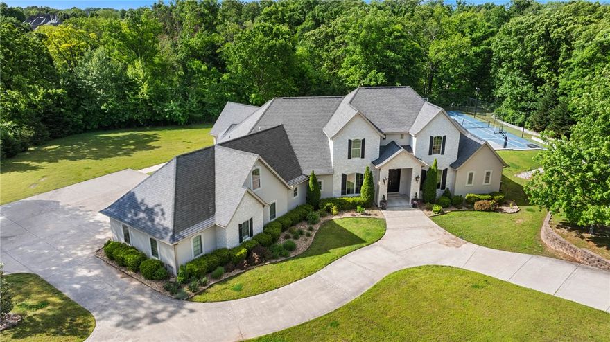 Located on 2.86 private acres in a prime Rogers location near shopping, hospitals, dining & XNA, this exceptional estate offers luxury, recreation & privacy w/no HOA or fees. Designed for both everyday living & unforgettable entertaining, the home features 5 bdrms, 3.5 baths, and beautifully curated living spaces throughout. A formal living room welcomes you with coffered ceilings, a fireplace & custom wine storage, while the expansive chef’s kitchen is equipped with dual islands, a gas range, double ovens & opens seamlessly to the family room overlooking the resort-style backyard. The spacious primary suite offers a private sitting area with peaceful backyard views. Step outside to an extraordinary outdoor oasis complete with a full kitchen with pizza oven, heated pool with dramatic fire & waterfall features, oversized hot tub, fire pit area & full basketball, tennis, and pickleball court. A truly rare offering combining privacy, luxury & unmatched amenities in one of Northwest Arkansas’ most desirable locations.