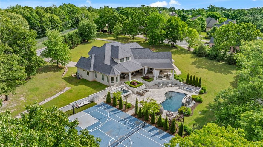 Located on 2.86 private acres in a prime Rogers location near shopping, hospitals, dining & XNA, this exceptional estate offers luxury, recreation & privacy w/no HOA or fees. Designed for both everyday living & unforgettable entertaining, the home features 5 bdrms, 3.5 baths, and beautifully curated living spaces throughout. A formal living room welcomes you with coffered ceilings, a fireplace & custom wine storage, while the expansive chef’s kitchen is equipped with dual islands, a gas range, double ovens & opens seamlessly to the family room overlooking the resort-style backyard. The spacious primary suite offers a private sitting area with peaceful backyard views. Step outside to an extraordinary outdoor oasis complete with a full kitchen with pizza oven, heated pool with dramatic fire & waterfall features, oversized hot tub, fire pit area & full basketball, tennis, and pickleball court. A truly rare offering combining privacy, luxury & unmatched amenities in one of Northwest Arkansas’ most desirable locations.