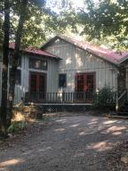 It's finally here! The private retreat you've been waiting for! Prepare for frequent visitors, from hummingbirds and deer to envious friends and family! This awesome porch is private enough to keep all to yourself and still large enough to share! Gorgeous entry, large master suite, wood burning stove, large bonus space and beautiful kitchen make the inside better than perfect. Large storage barn with tack room and heated and cooled shop, big barn with stables, covered RV storage with hookups, 2 room cabin, chicken coop and a pond are all yours too! Well, you might have to share the pond with the ducks and a Blue Heron or two. Nature trails abound with blueberries, grapes, and asparagus grown on property. This property is on Tri-County water, but also has a fully functioning well.