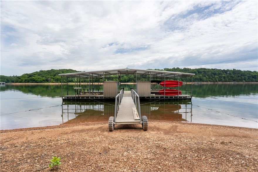 Back on market due to no fault of sellers. Beautiful lakefront home offers everything you would expect from a designer lake home oasis. Entering the home you're impressed w/high-end finishes & natural light. There is 2 family living areas, 2 fireplaces w/heatilators & a bonus room. Kitchen has a large island w/sitting for 6, separate coffee bar & walk in pantry. Enter the spacious primary suite on the main level thru 2 glass french doors. This home offers a whole house fan. Safe room located under the stairwell. Cedar closet & solid maple cabinets in the utility room. Patio has stamped concrete flooring, 1 deck has porcelain tile flooring, 2nd deck has tiger wood flooring. Home has hand-scraped hickory flooring. .91 acre of a manicured lawn, RV storage w/30 amp electric service, 3 car garage w/workshop & 2nd workshop in basement. There is a gentle walk way down to the private 4 stall boat dock w/swim deck. Home is located in highly desirable neighborhood. Only 5 minutes to Rogers & close to the marina.