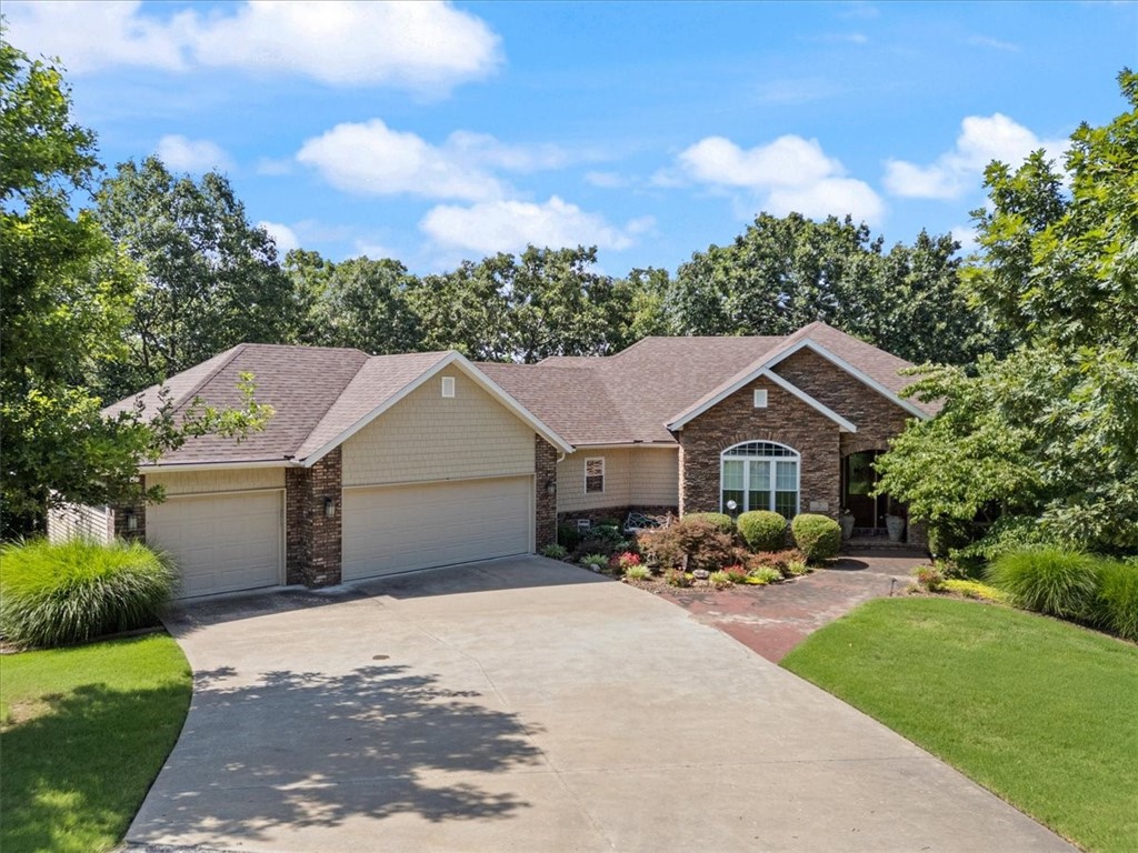 Nestled on a beautiful 1.73 acre lot, surrounded by landscaped gardens and mature trees. The 3 car garage, stone accents, and solid wood front door welcome you to this custom designed property. The living room is an inviting retreat, with 11 foot ceiling, a stone fireplace and built in bookcases with a wall of windows overlooking the wooded back yard. Wood flooring leads into the dining area and kitchen, with an abundance of granite counters, wood cabinetry with under cabinet lighting and additional bar top seating. The four season sunroom gives the feeling of being in a treehouse, with access from the dining area and primary suite. The primary suite and bath feature a large closet with access to the laundry. The perfect home office completes the main level. The lower level has a living area with bar sink and wine refrigerator, two spacious bedrooms and full bath. Additional finished space could be used as a game room, home theater or workshop. The patio and outdoor kitchen are perfect for entertaining! Gorgeous!