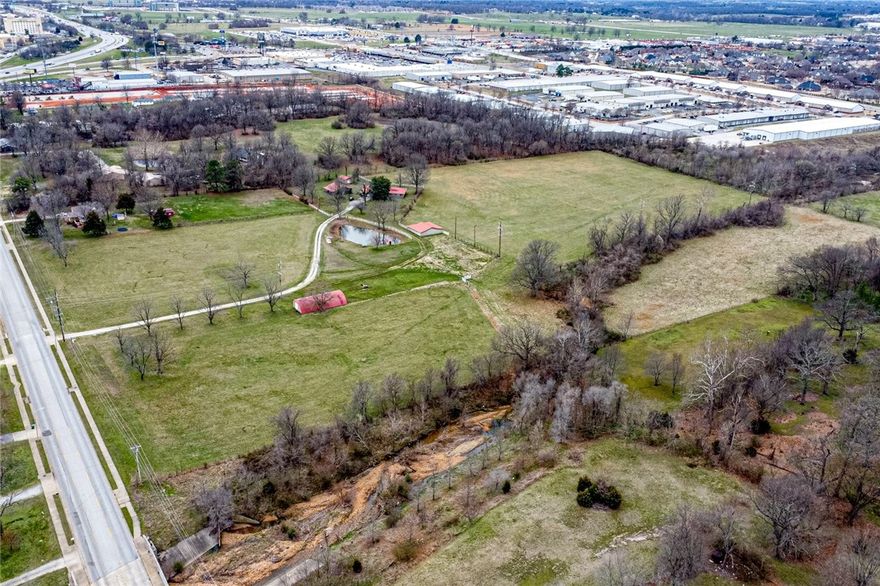 POTENTIAL DEVELOPMENT OPPORTUNITY! This 23 acres +/- is located near the hub of West Springdale!  East side of property along 48th street which provides close access to two on-ramps on I-49! West side of the property backs up to Oak Grove Montessori School & a shopping center! With this much acreage, the potential options are endless from a subdivision to multi-family to commercial possibilities like storage units, retail, and more! Land also features a 2,026 Sqft Home, pond, wet-weather creek, and outbuildings! *Property is subject to re-zoning. Don't let this opportunity pass you by!