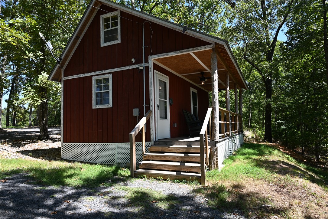 Fully furnished stick-built cabin on approx. 1.75 wooded acres in the heart of the Ozark Mountains! This cozy getaway features a loft bedroom, full bath, living area, washer, dryer, fridge, 2-burner cooktop, toaster oven, and microwave—everything needed for full-time living. Outside, enjoy a hot tub, beautiful pavilion, and a 10’x24’ storage building. Located on a quiet dead-end road with rural water, electric, and septic system in place. Currently a very popular Airbnb known as “Windstorm Cabin,” but also perfect as your own personal “Tiny House.” Enjoy peaceful surroundings, a nice view of distant mountains, and easy access to Branson, MO, the Buffalo National River, White River trout fishing, and 3 major lakes. Only 1.75 miles of dirt road and less than 9 miles to town. A turnkey retreat with income potential or a private escape in the Ozarks!