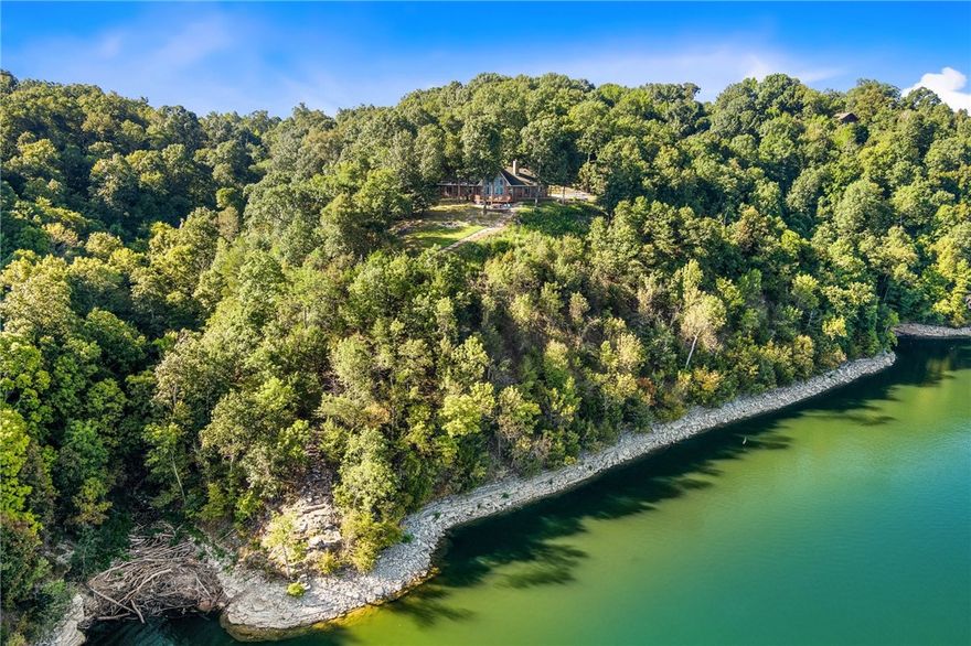 How about this view? Every room in this fully furnished custom home captures a stunning, panoramic view with 750 feet of shoreline. Currently a high-performing VRBO, it comes with an established listing and impressive rental history. Tucked away on 9.3 acres, the property is off-grid capable with well water, solar panels and battery storage. Inside, you'll find soaring 14-foot cathedral ceilings, an open layout, custom cabinetry, granite counters, and stainless appliances. All three bedrooms have terrific views and open directly onto the expansive back deck overlooking the lake. Additional features include an 8-person sauna, hot tub, a large fire pit, and two sets of stairs leading down to the water for swimming, fishing, or paddling out in a canoe. Slab is in place for adding a garage or adding additional square footage. Several building spots on the property for shops, cabins or more homes if desired. So many options with this estate!