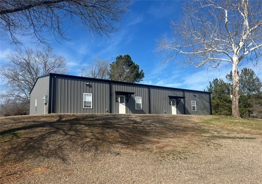 Need the perfect place for your new business, or a new place for your existing business?  This 3200 sq ft facility sits on 1.17 acres, just a block off of Hwy 7. Custom designed in 2023 with focus on beauty and function. The south side of the building features a 2000 sq ft design studio/retail space, with abundant lighting, luxury vinyl flooring, clean white walls and trim, half bath, full kitchen with dining area, social media photography room, and a 13x14 storage room. The open concept lends itself to a multitude of possibilities to customize the space to suit your needs! Down the hall you’ll enter into a 1200 sq ft warehouse space, with a large insulated overhead door, half bath, high ceilings, 3 ton ductless heat and air unit for comfort, and 2 additional exterior doors. The state of the art security system lets you keep an eye on your space while you’re away. Large green space in the back, several mature trees, large gravel parking area, and a circle drive. Plenty of room to add on if needed.