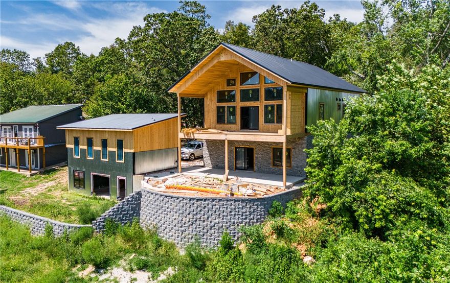 Welcome to your dream retreat! Nestled in the serene Monte Ne area, this stunning new construction cabin near Beaver Lake offers 3 bedrooms, 5.5 bathrooms, and 4100 sq ft. The exterior features corrugated metal and cedar, blending modern and cozy. Enjoy year-round lake and mountain views. The downstairs area could serve as a mother-in-law suite. Luxurious white oak floors and quartz/granite countertops add elegance. Cozy up by the two fireplaces. A separate shop with its own living area, kitchen, and bathroom provides extra space. The 2-car garage includes a bathroom and climate control. There’s also a hot tub hookup at the property. Less than 5 minutes away from Monte Ne boat ramp. Construction completes by the end of September. Don't miss out on this extraordinary lakefront cabin!