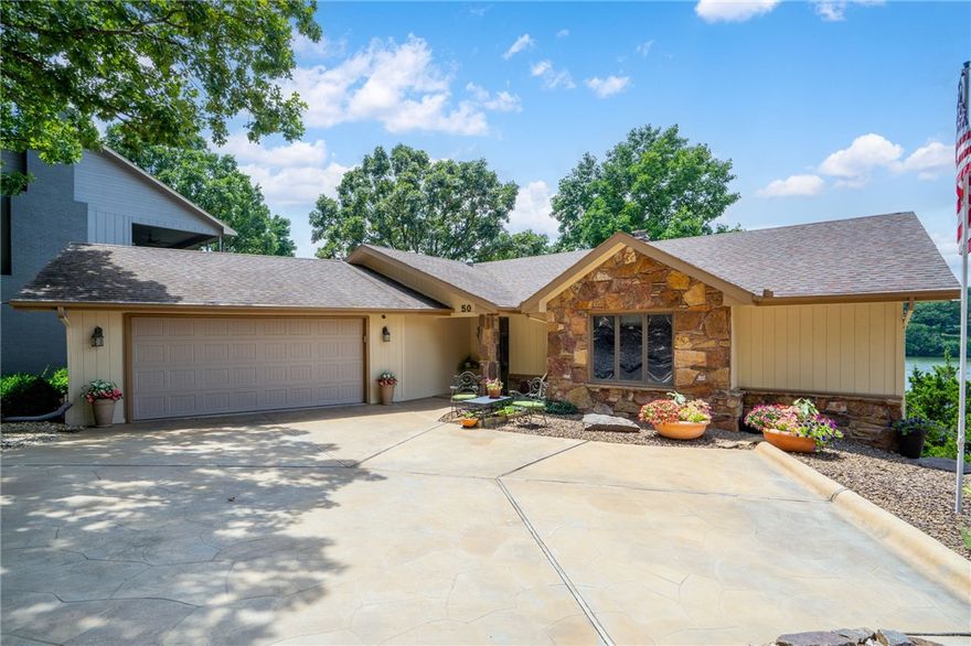 Enjoy stunning lake views from every room in this exceptional home built by Gene Knight, complete with the luxury of a private dock just steps from your back door. Designed to impress, the open-concept main living area features soaring vaulted ceilings with exposed beams and expansive windows that seamlessly merge indoor and outdoor living. The main level includes a tranquil primary suite and a home office. On the lower level, you'll find an additional bedroom, guest room, full bathroom, work room, and a spacious family room—ideal for relaxing or entertaining. Recently updated with meticulous attention to detail, this home offers a seamless connection to the water and invites you to experience the unmatched beauty of lakefront living. Epoxy garage floor and storage. The intelligently designed driveway channels water away from the home via a spillway. Expanded parking at street level for guests and visitors. Just 9 minutes from the Walmart Home Office with easy access to I-49 and in the Bentonville School District.