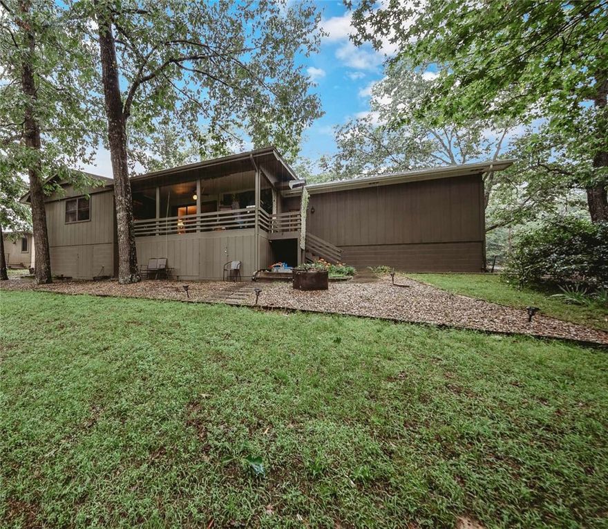 Partial lake view, lake access; woods in front. Short walk on trail to Tanyard Creek and waterfall. Quiet and private. Large living room leads out to covered deck. Large kitchen with bar, beautiful wood cabinetry with slide outs; Dining area overlooks woods in front. Large master bedroom with master bath and seasonal lake view. Spring and summer feels like living in a treehouse! Second bedroom has wooded view. Soft, luxurious, high-quality nylon carpet throughout. Extremely energy-efficient heat pump. Natural stone fireplace with forced-air heating option. Smart thermostat—adjust temperature from your bed (or anywhere.) Super clean under-house storage or workshop. 2 storage areas. Oversized two-car garage. New roof 2020. Unobtrusive backyard fencing can convey—or be easily taken down; buyer’s choice. This home is rich in character, built with quality and integrity.