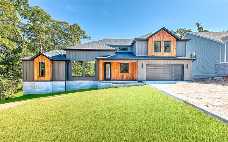 Welcome home to stunning new construction in Bella Vista. This traditional home has a contemporary edge with striking black finishes and warm cedar trim. The open-concept floor plan is flooded with natural light, featuring a spacious living area and an impressive kitchen. Perfect for entertaining, the kitchen boasts a waterfall island and sleek appliances. Enjoy the cozy living room, fireplace, and a view of your secluded backyard. The main level features the primary suite, a private retreat with a luxurious en-suite bath and a huge walk-in closet. Upstairs, you'll find two generous bedrooms and a flexible bonus room ideal for an office or media space. Step out to the covered deck to enjoy coffee overlooking the peaceful, wooded surroundings. Bella Vista is a haven for outdoor enthusiasts, offering golf courses, lakes, and over 100 miles of world-class trails. The state's first mountain biking chairlift is also coming soon! This home is the perfect blend of modern luxury and unparalleled outdoor access.