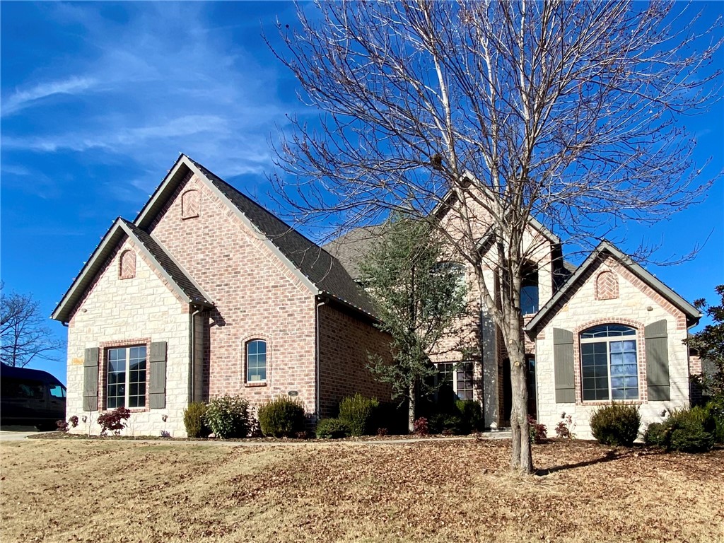 Nestled in the Oak Tree gated community, this custom home is perfect for all that Northwest Arkansas has to offer. Oak wood floors, a stone fireplace and expansive windows welcome you. The kitchen features custom cabinetry, a pantry, double oven, gas cooktop, granite countertops, and an island. The main floor hosts the living room, master bedroom with full ensuite bath and walk-in closet, an additional bedroom and bathroom, and an office/dining area. A 3 car garage and side driveway provide access. Step outside to a rare huge flat backyard with a privacy fence, expansive open views, and a covered patio with a grill and fireplace. Upstairs 3 bedrooms, 2 baths, and a movie room with a wet bar and beer tap system. Oak Tree provides an ideal setting for kids and adults, amenities include a playground, tennis, pickleball and basketball courts, a community pool and clubhouse, and kind family-oriented neighbors. Nearby are Bentonville schools (West HS), biking trails (Coler and Little Sugar), and downtown Bentonville.