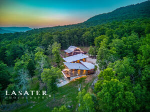 Welcome to your own private sanctuary! This exquisite home nestled on 47 acres of picturesque land in Newton County, Arkansas joins the Ozark National Forest. The 2BR, 2BA 2,048 sf main residence offers high-quality finishes and an abundance of natural light. Includes an expansive porch for enjoying scenic views and outdoor gatherings. Open-concept kitchen and living area, ideal for entertaining guests. Spacious layout, exceptional outdoor lighting, and luxurious amenities. There is a large, 32x25 detached 2 car garage w/10x10 doors that boast a separate 1BR 1BA 480 sf apartment, a beautiful 40x50 wood barn w/ 10' side sheds, a 160 sf 1BR 1BA bunk room and ample space for outdoor activities. This stunning property is a true gem for those seeking a peaceful & refined country lifestyle!