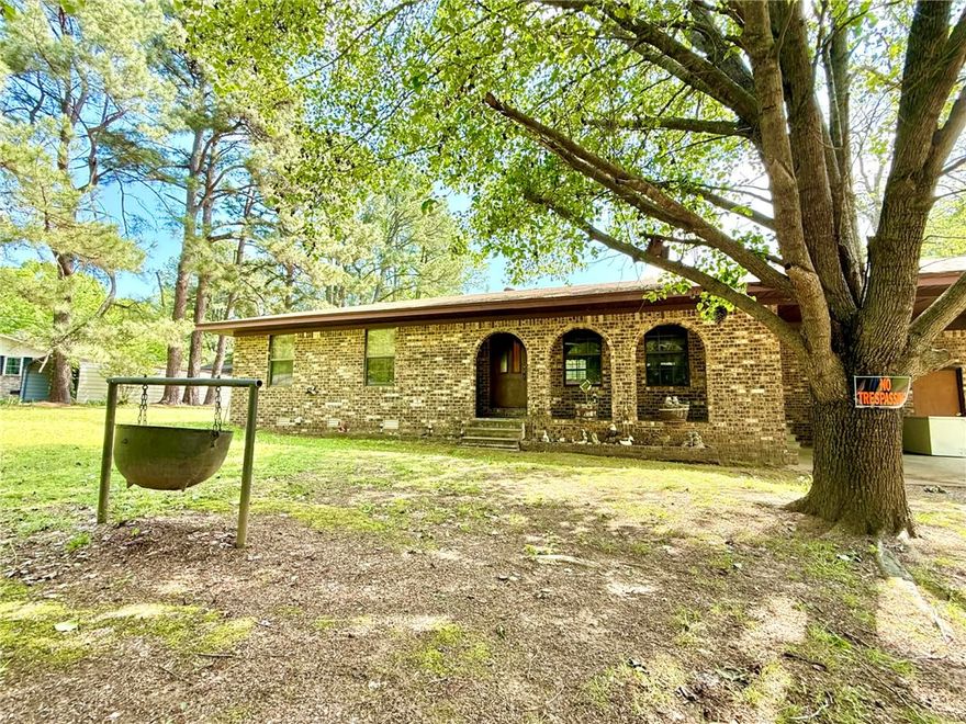 Charming 3-bedroom, 1.5-bath brick home on 1.8 acres in Atkins city limits! Offering 1,324 sq ft, this home features an open-concept living, dining, and kitchen area, central HVAC, carpet flooring, and a functional layout with the primary bedroom including a private half bath. Enjoy the convenience of an attached carport with direct access to the laundry room. Step outside to a back patio overlooking the huge backyard, complete with outbuildings and plenty of space for gardening, outdoor living, or creating your own private oasis. Connected to city water and sewer, with trash included in water service, this property is a blank slate ready for your personal touch and updates!