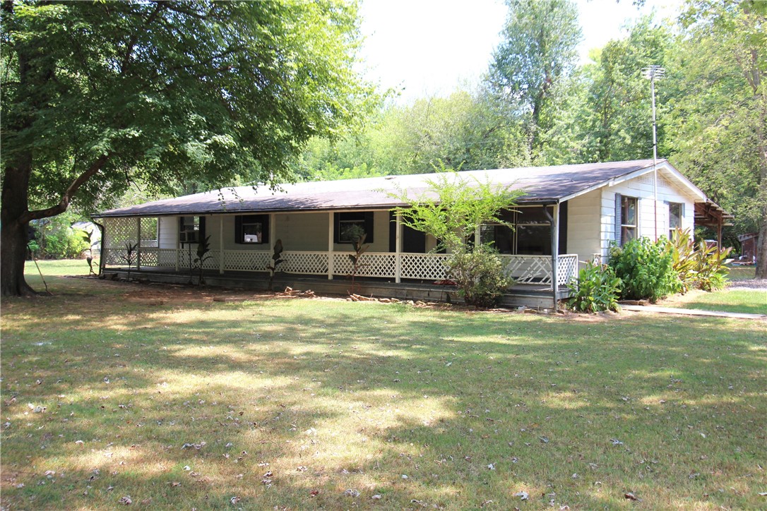 Double wide mobile home with metal siding, covered front and back porches on nearly half an acre. Laminate & vinly flooring throughout the home, no carpet. Plenty of closet space. The property has several mature shade trees. Convenient location near shopping, schools, park and I-49 access. Being sold "As Is". Additional adjoining home and property available.