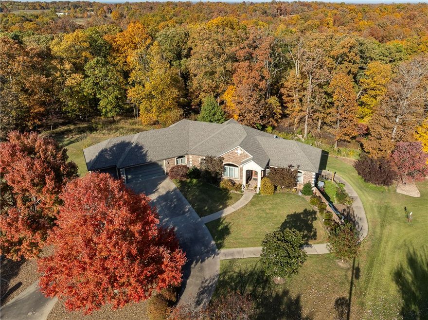 A space for everything and everybody. This O.A.K.–built home offers exceptional quality with 11’ ceilings, solid oak floors, poured-concrete foundation, and rare privacy on three lots totaling .98 acres. Enjoy stargazing from your deck, pick fruit from mature plants, or simply unwind in total seclusion. Inside, you’ll find two fireplaces (including a brick-surround Kozy Heat gas log), a wall of windows overlooking the patio, and 1,100+ sq ft of climate-controlled storage plus a 3-car garage with concrete circular drive and full house back-up generator. The lower level is ideal for multi-generational living with a large wet bar, full-size refrigerator, storage under the stairs, full bath, spacious bedroom, and interior workshop with workbench, utility sink, and  HVAC. Double doors open to a private patio. Close to lakes, golf, and walking trails—this home blends comfort, function, and nature.