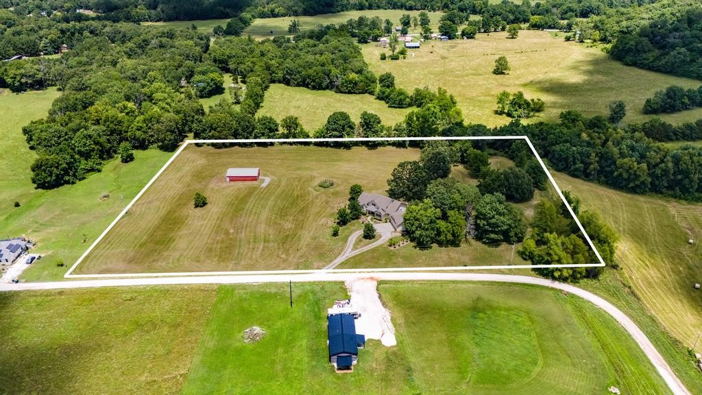 Welcome to 588 Red Hawk Rd in West Fork, Arkansas. This traditional farmhouse sits on 6.85 acres with a pond, garden and 30x50 barn. Located just 15 minutes from University of Arkansas and 4 miles from Drake Field, this property provides privacy with proximity to Fayetteville. Beautiful hardwood floors flow throughout the living room, dining room, foyer and primary bedroom suite. Details are found throughout the house . . . crown molding, built in bookshelves, wood burning stone fireplace, extra cabinets in the laundry room. Kitchen features a pantry, stainless appliances and tall glass cabinets that extend to the ceiling. Primary suite is on the main floor with 2 bedrooms & a bonus room upstairs. Two extra rooms on the main floor can be used as an office, exercise room or bedroom (without closets). Access the large deck from the kitchen or the primary suite. Breezeway provides access to the oversized 2-car garage. Orchard includes many native drought resistant varieties of trees.