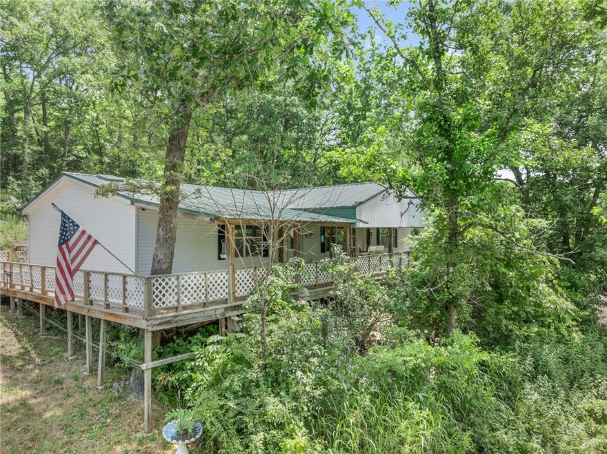 Ozarks retreat between Branson & Harrison! Enjoy peaceful living on 5 mostly wooded acres (m/l) along beautiful Cricket Creek, approx. 200 yards from Table Rock Lake (less than 15 minutes to marina). Well-maintained 3BR, 2BA, approx. 1680 sq. ft. manufactured home offers spacious eat-in kitchen, living room, den, pantry, & laundry room—perfect for full-time living or weekend getaway. Relax on the covered lg front porch with a swing & take in the natural setting. Extras include Taylor outdoor wood-burning furnace for backup heat & hot water, 20x20 metal shop w/electric, water, wood heat, 8' roll-up door, & 10' lean-to, two 8x16 storage buildings w/12' lean-to, & new well house. Great location & setup for outdoor hobbyists, or anyone looking for a quiet place in the Ozarks! Does not qualify for FHA/RD/VA loans.