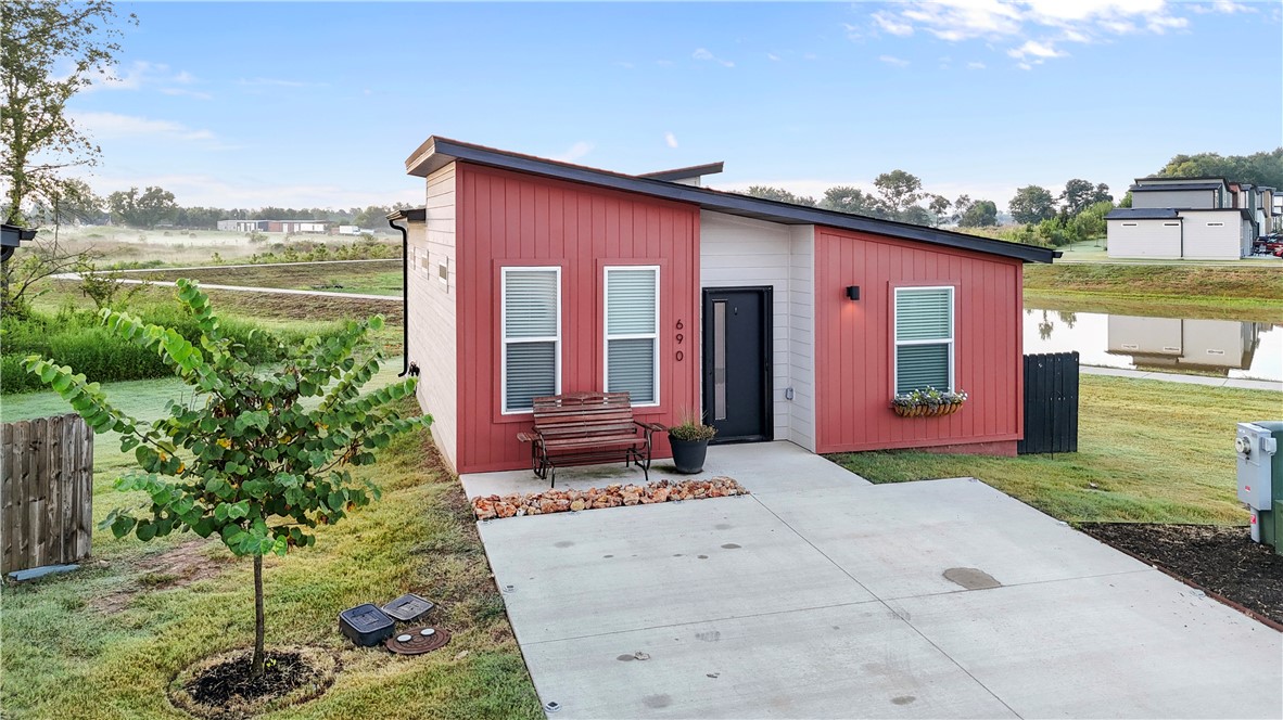 Discover the epitome of modern living in this adorable micro home! Nestled on what is arguably the best lot in the neighborhood, this property boasts serene pond views, breathtaking sunrises, no neighbors to the right and a secluded back patio from a cleverly positioned house. Step out onto the walking trail right from your backyard, leading directly to the dog park and pickleball court for endless recreation. The home offers easy access to mountain bike trails and other local attractions. Inside, you'll find soft-close kitchen cabinets with custom organization and energy-efficient windows that tilt in for easy cleaning. Retractable screen doors, Custom solar lighting, wainscoting, Murphy bed, appliances, kitchen counters, backsplash, enlarged patio, custom landscaping and wildflower garden have all been upgraded from builder spec. POA $75 a month, including yard care. Less than 15 minutes from the Bentonville square and WM home office. For the right offer, all appliances and most furnishings can be included!