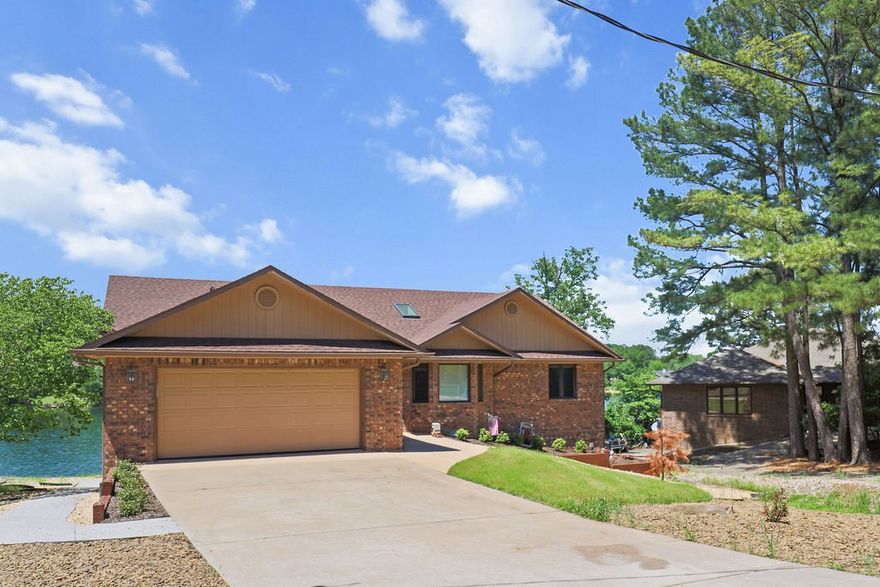 Stunning lakefront corner property with panoramic 180+ degree water views! This brick-front home features a beautifully landscaped yard with a flat walkout to your private dock—no steep stairs to navigate. Inside, discover thoughtful updates throughout. The unique round office with elevated ceilings and built-in plant shelving adds character, while the spacious master suite offers a huge walk-in closet and private bath. Enjoy lakeside living from your screened porch or multi-level deck. The finished basement includes comfortable carpeting, a gas fireplace, additional bedrooms with gorgeous views, and a full bath. Recent updates include completely refreshed landscaping. This turnkey property blends modern conveniences with breathtaking natural beauty—perfectly positioned to maximize those spectacular sunrise-to-sunset lake views from nearly every room.