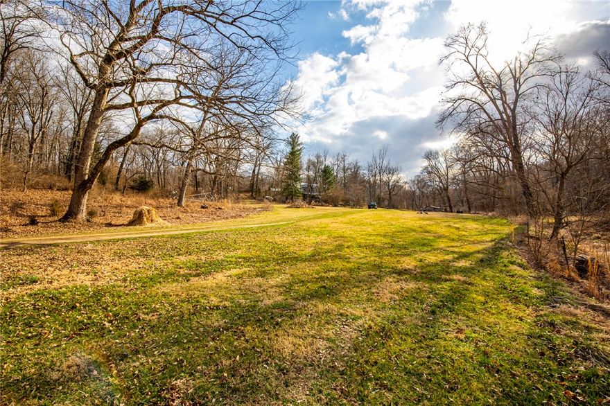 Stunning farmhouse homestead on nearly 70 acres a couple of minutes to Downtown Rogers. Enjoy a one of a kind property that has a creek/pond, and multiple areas to develop, or just enjoy the scenic beauty of this land with a beautiful valley, wooded ridgeline, pond, developable 35 acres. Inside you'll find a one of a home kind with real tree wood beams, bricks from a Neosho train station, native stone, and custom door/porch.  This would make a wonderful farm, corporate retreat setting, camp location, run horses, and so much more. This is sold as is. To access to approx 35 acres on the ridge, you'll need 4 wheel drive truck or suv, no cars/small vehicles.