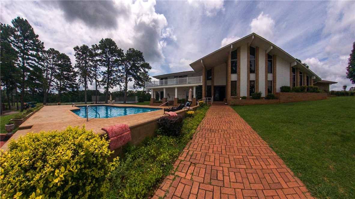 Architecture history defined in this unique, custom built, one owner home. The original blueprints from Mott, Mobley, Horstman & Griffin Architects from 1973 will be a highlight to engage you in every detail of this home. These high profile architects are known for their structures such as Bud Walton Arena, AR Courthouses, U of A Yoakum Hall & more. The structural integrity of this home will hopefully impress you and your home inspector! 2 story with a 40' peak highlighting some of the 250k bricks used on this property. Swimming pool, tennis court, 39 Hay/Income producing acres of pasture, chef's kitchen, sauna, vinyl fencing, ponds, Million $ views and wide open spaces combined with a neutral pallet for a fresh new contemporary eye to bring out its truly unique character. The guesthouse also has the potential for rental income or in-law quarters. No words...you must see this one in person.