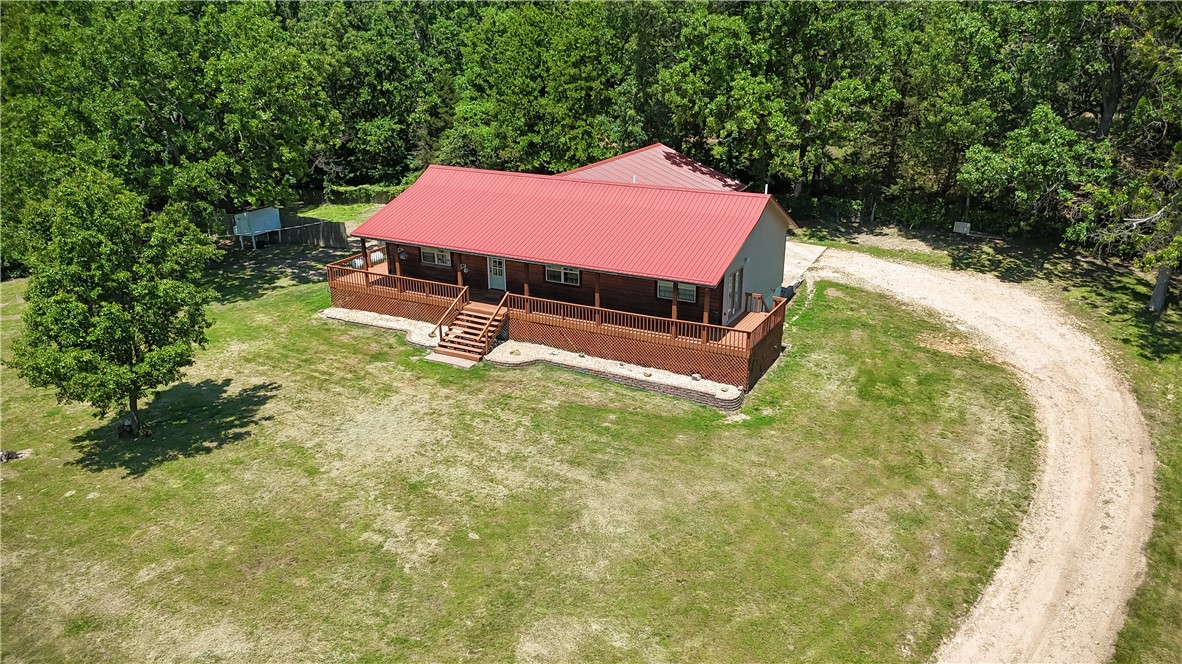 Rural, spacious, and practical. This updated 5-bedroom, 3-bathroom home offers over 2,300 sq ft of living space on 1 acre, minutes from Harrison. The open-concept design connects the living room with its cathedral ceilings and gas fireplace to the farmhouse-inspired eat-in kitchen, creating an inviting atmosphere for gathering or entertaining. The primary suite features a private bathroom, walk-in closet, cathedral ceilings, and a private exit onto the wraparound deck that adorns the front of the home. Notable attributes include a pull-through attached two-car garage, attached metal workshop area, metal roof, low maintenance vinyl and log siding, and a long private driveway with a gate, all in a desirable school district. This home combines the best of country living with modern efficiency.