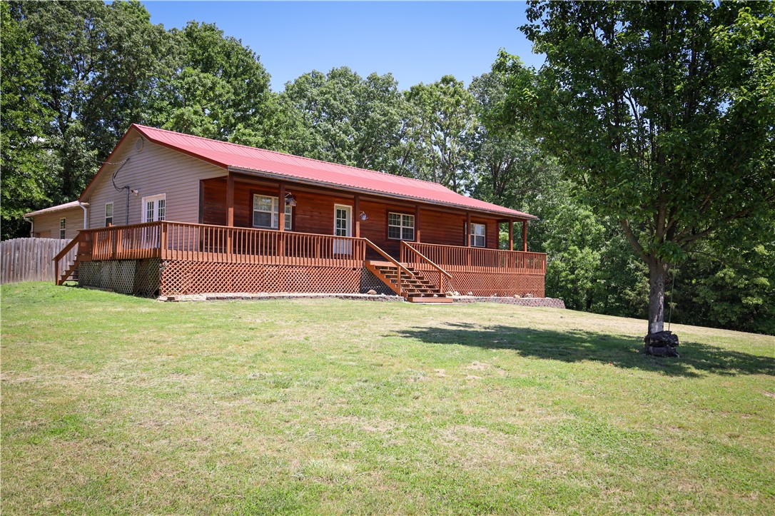 Rural, spacious, and practical. This updated 5-bedroom, 3-bathroom home offers over 2,300 sq ft of living space on 1 acre, minutes from Harrison. The open-concept design connects the living room with its cathedral ceilings and gas fireplace to the farmhouse-inspired eat-in kitchen, creating an inviting atmosphere for gathering or entertaining. The primary suite features a private bathroom, walk-in closet, cathedral ceilings, and a private exit onto the wraparound deck that adorns the front of the home. Notable attributes include a pull-through attached two-car garage, attached metal workshop area, metal roof, low maintenance vinyl and log siding, and a long private driveway with a gate, all in a desirable school district. This home combines the best of country living with modern efficiency.