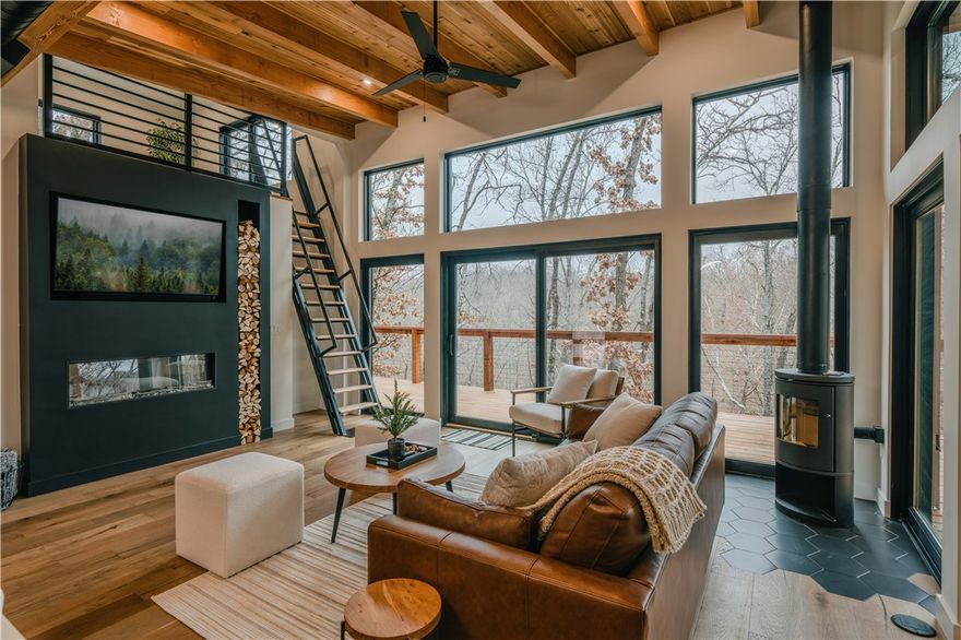 The "Ozark Modern Retreat" is a beautifully constructed cabin offering a blend of contemporary design and natural beauty. Currently operating as a successful Airbnb, this property is an exceptional opportunity for investors or buyers seeking a retreat. Nestled in the woods near Beaver Lake, the home showcases sleek modern architecture with expansive windows and sliding glass doors with panoramic views. The open-concept living area features a well-appointed kitchen, modern finishes, and a cozy fireplace. The primary suite offers a picture window overlooking the woods, while the bathroom includes a soaking tub and walk-in shower. A loft space provides additional sleeping accommodations. Outdoor living is a highlight, with a large deck, covered patio, and fire pit area. Located near Beaver Lake and 30 minutes to Bentonville, this property offers privacy while not being too far from town. Whether used as a short-term rental or private getaway, this modern retreat offers a versatile opportunity in Northwest Arkansas.