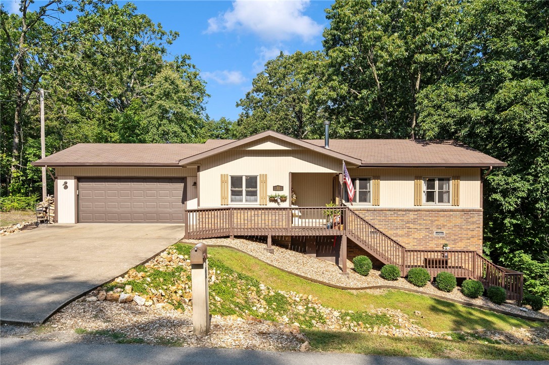 This inviting Bella Vista home blends warmth and charm in a beautifully landscaped setting. Inside, you will discover a cozy living area wrapped in natural tones, complete with a wood-burning fireplace offering added heat in the winter. The screened-in porch expands your living space, welcoming year-round enjoyment. A former carport has been enclosed into a 2-car garage with a mini-split system, providing climate control and added versatility. Below the home, a ~160 sq.ft. crawlspace is currently used as a music room- a bonus area full of creative potential. Additionally, no carpet throughout ensures easy upkeep, and both the front and backyard are landscaped to enhance curb appeal and create an outdoor retreat. With a brand new roof to be installed, refreshed front and back decking, and an updated primary shower, it's move-in ready with room to make it your own. Located less than a mile from Branchwood Rec Center and easy access to I-49, this home provides accessible amenities and convenience.