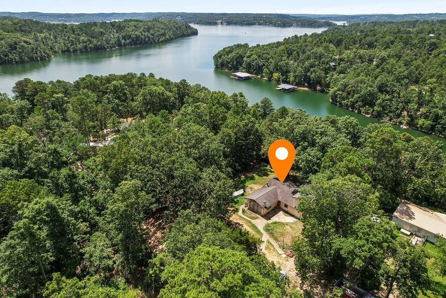 Great opportunity on Beaver Lake! Property includes two parcels,  totaling nearly one acre (.90 acres) with seasonal lake views and close access to a nearby boat ramp. The 1,964 sq ft home needs work but offers great potential. The spacious private primary suite features tile floors, vaulted porch-ceiling, built-in dressers. The primary bath includes a large corner tub. Enjoy a sunken living room with a wall of windows and cathedral ceiling, plus an open floor plan connecting the kitchen, dining, and living areas with an additional bonus room. Property backs up to Corps of Engineers land with lake frontage. Wooded and open areas provide privacy and space to enjoy the outdoors. Seasonal lake view and open areas offer privacy & natural beauty of Northwest Arkansas surrounds you—perfect for quiet mornings, lake adventures, and peaceful living in a breathtaking setting. This property does not have a boat dock. To be sold "As is" -will not qualify for traditional financing.