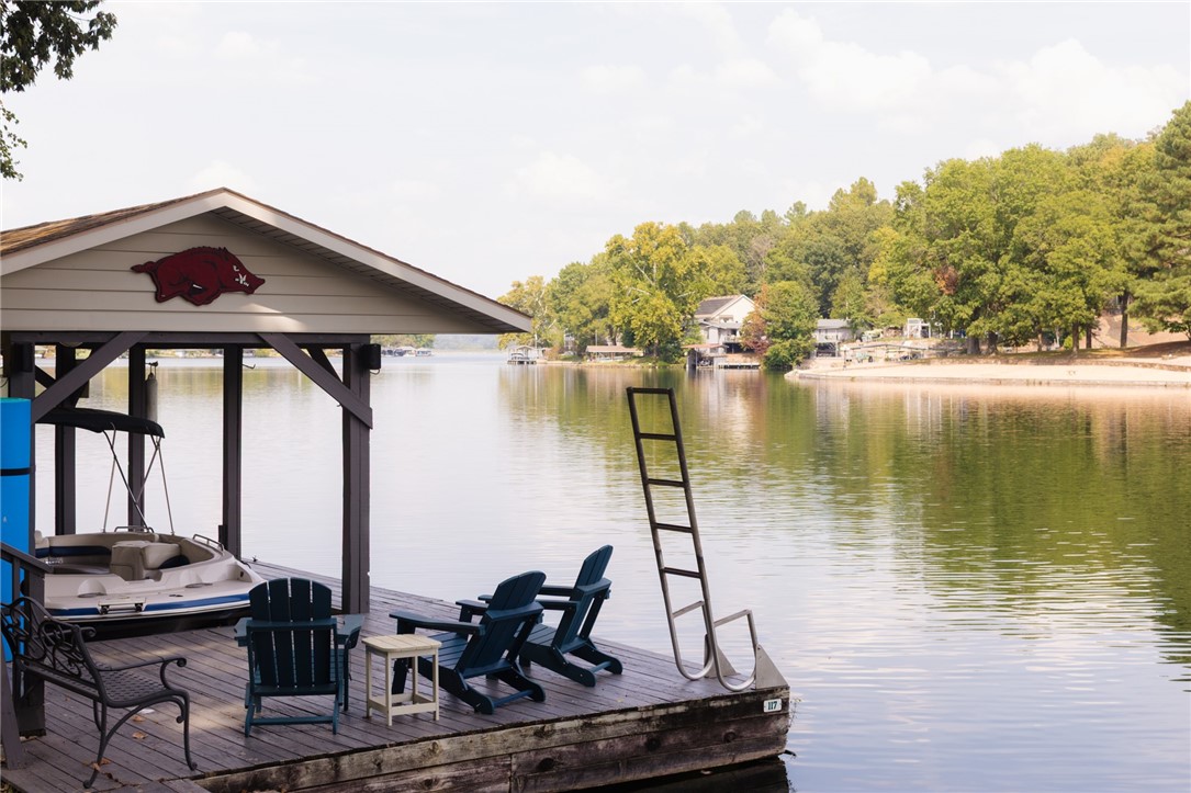Gorgeous Lake Front Home w/ Private Dock! This 4-bedroom home features a great layout, large circle drive, and 3 level outdoor living space. The main level living space has beautiful tongue & groove ship lap ceiling w/ wood beam. Living room has brick wood burning fireplace & stunning lake views. Kitchen has been renovated w/new appliances & granite counters. Primary bedroom on main level w/fully remodeled bath w/ large walk-in shower, double vanity & WIC. Two guest beds and one bath on other side of the home. Downstairs is a full second living area with living space & full kitchen. One full bath/laundry. 4th bedroom has attached bath. Flex room for 5th bed/office/game room. Enjoy your lakeside setting from the expansive outdoor living areas, both covered and uncovered decks as well as stairs to your private boat/swim dock! Workshop under the home w/crawlspace storage. Easily accessible to Bentonville & I-49. Community amenities include golf, lakes, mountain biking trails & downhill park, gyms, pools & more!