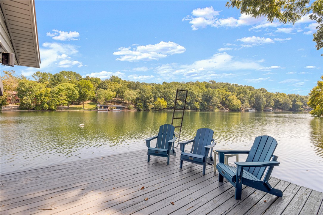 Gorgeous Lake Front Home w/ Private Dock! This 4-bedroom home features a great layout, large circle drive, and 3 level outdoor living space. The main level living space has beautiful tongue & groove ship lap ceiling w/ wood beam. Living room has brick wood burning fireplace & stunning lake views. Kitchen has been renovated w/new appliances & granite counters. Primary bedroom on main level w/fully remodeled bath w/ large walk-in shower, double vanity & WIC. Two guest beds and one bath on other side of the home. Downstairs is a full second living area with living space & full kitchen. One full bath/laundry. 4th bedroom has attached bath. Flex room for 5th bed/office/game room. Enjoy your lakeside setting from the expansive outdoor living areas, both covered and uncovered decks as well as stairs to your private boat/swim dock! Workshop under the home w/crawlspace storage. Easily accessible to Bentonville & I-49. Community amenities include golf, lakes, mountain biking trails & downhill park, gyms, pools & more!