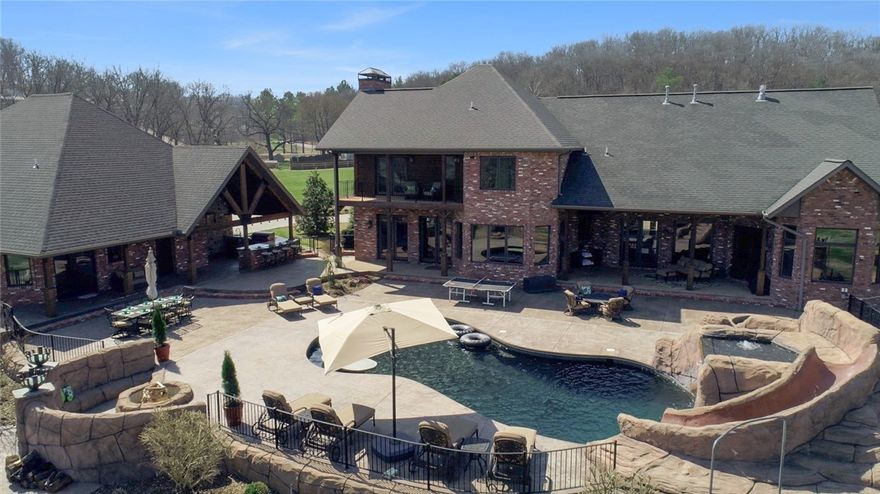 SPECTACULAR CUSTOM BUILT ESTATE WITH PRIVATE RESORT STYLE OUTDOOR PARADISE TUCKED AWAY ON OVER 5 ACRES WITH CREEK FRONTAGE, CUSTOM IN-GROUND POOL WITH WATERFALL AND SLIDE, HOT TUB, FULL OUTDOOR KITCHEN, EXTENSIVE PATIO SPACE, SURROUND SOUND, FIRE PIT, 180 YARD PAR 3 TARGET GREEN….TRULY AN ENTERTAINER’S DREAM!!  The gorgeous main house boasts a spacious chef’s kitchen w/professional grade appliances, private master retreat w/luxurious en suite bath and amazing walk-in closet, main level guest suite, executive office w/ fireplace, large formal dining, upstairs media room w/wet bar & more!  Fabulous 1,400 sq ft guest home with disabled access, full kitchen, master suite, guest bed & bath, living w/fireplace….ideal for an in-law quarters, Airbnb or a place to host friends.  Beautiful knotty alder custom cabinetry, stone arches, hardwood floors, built-ins, storm shelter, storage galore & more.  Enjoy resort like living every day all just minutes away from some of NWA’s best shopping, dining and entertainment!