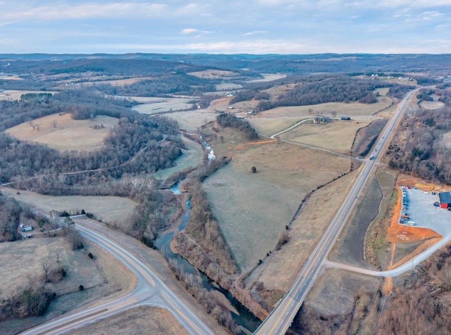 Prime 25.5± acre opportunity in Huntsville, AR with highway frontage on Hwy 412 and excellent visibility. Zoned DUZ (Dual Use Zone) allowing C-2 or R-1, offering flexibility for commercial development, investment, or a future homesite. Convenient access near Hwy 23 with city water, sewer, electric, and fiber available. Holman Creek runs along the eastern edge, adding character and natural beauty. Located in a rapidly growing area with strong daily traffic counts.