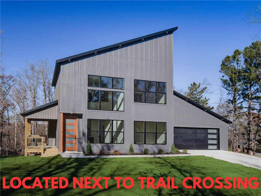 This modern new construction home sits on a wooded .34 acre lot! Located next to trail crossing and down the street from the Back 40 Trailhead! Only minutes to Lake Ann! This stunning home showcases modern high-end finishes throughout! Step inside to discover beautiful custom cabinets and a huge waterfall island, perfect for entertaining family and friends. The kitchen is also equipped with sleek stainless steel appliances, including a gas range. Hardwood floors. No carpet! Breathtaking two-story living room with huge windows going up to the ceiling! Retreat to the primary suite with high ceilings and a stunning walk-in tile shower that elevates your everyday routine. Guest bedroom is located on the main level. Bentonville schools! As a bonus, the buyer can receive $3,500 in closing costs when using the builder's preferred lender.