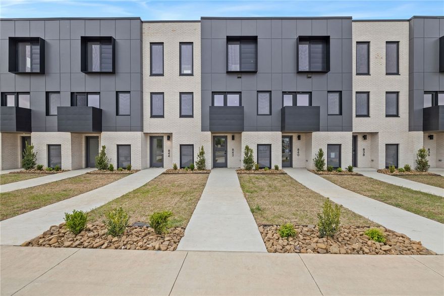 Enjoy the best of downtown Bentonville living in this luxury Lightbox townhome—designed for ones who want walkability, style, and smart design. Located just one block from the new Walmart Home Office campus and directly across from 8th Street Market, this North Light residence offers expansive northern views, including the Momentary. The architecturally striking design allows natural light to pour in from third-floor clerestory windows down through the open stairwell to the main living level, creating a bright, calm, and modern feel throughout. The kitchen blends form and function with a European Bosch appliance package, induction range, white oak cabinetry, and bold quartz countertops. Across the catwalk, the living area is framed by oversized windows—perfect for relaxing or entertaining with a view. Upstairs, two private bedroom suites each feature their own bath, offering flexibility for guests, work-from-home space, or a refined second-home lifestyle—all just steps from Bentonville’s dining, arts, and trails.