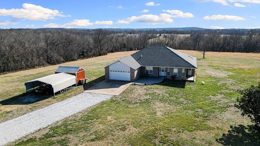 Escape to your own private 24.12-acre sanctuary in Garfield! This incredible property offers the perfect blend of secluded country living and modern efficiency, all within the Pea Ridge School District. The move-in-ready home features 3 bedrooms, 2.5 baths, an office, and a formal dining room. Recent upgrades include new hardwood flooring, updated lighting, a new HVAC system, a new roof, new epoxy front patio and updated landscaping with firepit. Efficiency is key with solar panels, a tankless water heater, and an owned propane tank. For peace of mind, the primary closet doubles as a large tornado shelter, and two ring cameras convey.  The acres are mostly flat, usable land features a pond, spring-fed creek, and perimeter trees. Outbuildings include a chicken coop, shed, and carport, plus an attached 2-car garage. Starlink internet conveys! Located just 16 minutes from Pea Ridge HS and seconds from the National Park trails. Note: Polaris ATV and tractor available for separate purchase. Your homestead awaits!