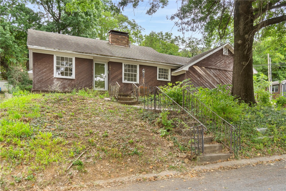 Discover the charm and potential of this delightful 2-bedroom, 1-bath home, nestled on a spacious corner lot adorned with lovely mature trees. This home, being sold as is, could use a little TLC but has endless possibilities. Featuring beautiful real wood floors throughout the living areas, a cozy wood-burning fireplace, and character-rich cedar siding, with abundant windows that offer lots of light and charm. Modern updates, including stainless steel appliances, some updated electrical and plumbing, blend seamlessly with the home's original features. The expansive backyard offers ample space for landscaping and outdoor living. Ideally situated just a short stroll from downtown and close to the University of Arkansas. Perfect home for a starter house, rental, flip or last home in a highly desirable area.