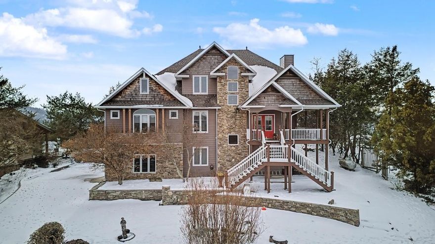 This stunning home is perched on a bluff with sweeping views of Table Rock Lake, Castle Rogue's Manor, the "Little Golden Gate Bridge" over the White River/Table Rock Lake in a historic town. Ascending the front steps, a covered porch leads to double entry doors. Inside, a grand living room boasts vaulted ceilings with a stone fireplace, wood floors and lake views. A large primary suite with deck access overlooking the limestone bluffs sits just off the kitchen and living area on the main level. The upper level offers a balcony overlooking the living room, sitting area, 2 bedrooms or bonus spaces and a bathroom. Downstairs, the basement features a bedroom, bath, living area and workshop plus garage access. The home is equipped for an elevator setup. Large deck areas maximize the home's viewing position, and terraced, stone-accented landscaping blends in subtly. Situated in the planned community of Holiday Island, this home offers access to the Table Rock Marina, recreation amenities, and a unique, vacation vibe.