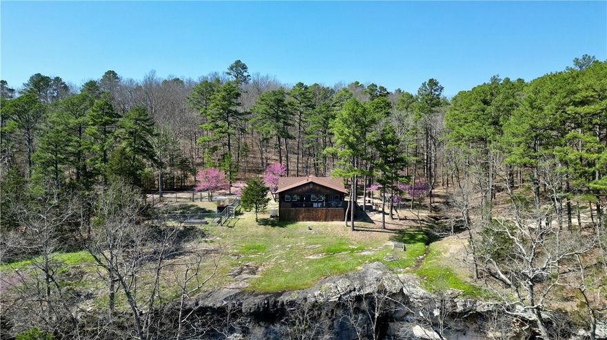 40-acre retreat surrounded by nature, AR game/Fish land & minutes from Kings River, this property offers serenity & adventure. Fully remodeled homestead seamlessly blends natural elements with modern design. A  gas fireplace & custom mantle  anchors the open concept kitchen & living area. The kitchen features new cabinets, ss appliances, quartz countertops & pantry. The split floorplan has a cozy primary bedroom with a luxurious spa-like ensuite, complete with a backlit defogging mirror, soaking tub, walk-in rain shower, & custom cedar vanity with a trough sink. 24x40 detached garage offers versatility for shop/gym w/ a woodstove for year-round use.  50'x50’ fenced garden w/raised beds & solar greenhouse. The thoughtfully designed glamping site provides opportunities for short-term rental or off-grid escapes. Explore wet-weather waterfalls, a creek, caves & private trails.  Relax & enjoy the stunning views over the bluff from the deck while savoring your morning coffee.