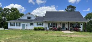 This is a gorgeous, country chic style home with extra-large front and back porches, setting upon a hill that provides a nice view. Home has 4 bdrms., 4 baths with rock front woodburning stove. Nice sized, open living area and dining room. Also, another area that can be used for living room or breakfast area. Split bdrm. plan, 4th bdrm.(14 x 20) & bath is accessed by stairs through laundry room. Double car garage attached and a detached garage/shop. On rural water, but also has a well, used for outdoor watering. Roof/2019. One electric heat pump unit new in summer of '21. Other original. New septic field lines in 2021. Sq. Ft. includes the addition of the upstairs bdrm.Bonus: Mother-in-Law quarters...1b/1b house in backyard, currently used as a workshop.