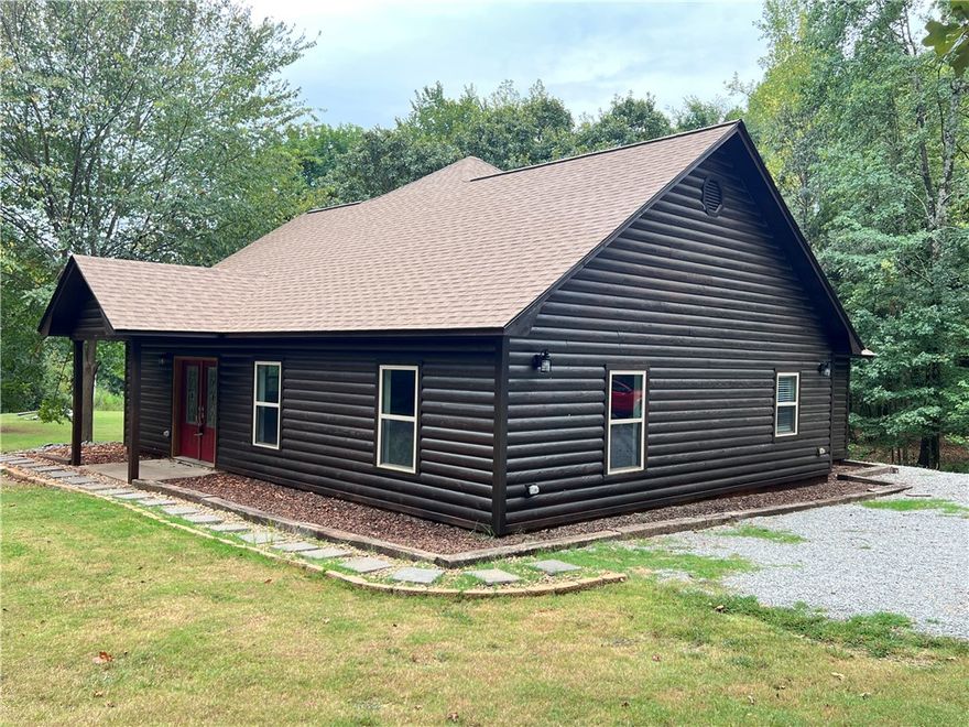 A well built 2400 square foot home on over 16 acres, just outside of Russellville city limits? Act now and be rocking on the back porch this fall! Enjoy country living with plenty of land for privacy and a wrap around porch that provides a gorgeous view!  In addition to the Log sided, 3 bedroom, 2 bath house, this property also comes with a 30x40 shop!  This metal building shop is equipped with full bath and living quarters when additional space is needed.  The RV and tractor parking canopies both convey and the equipment can be purchased separately. Each building comes with a refrigerator and a washer & dryer set. New roof in August of 2025!
