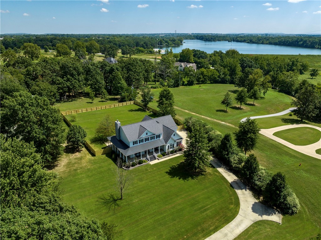 Southern Living Estate home with a wraparound covered porch sitting on 1 acre conveniently located in the middle of NWA! Beautiful hardwood flooring throughout! Formal dining, office, stunning kitchen with Butcher Block countertops and SS appliances, living room with vaulted ceiling, floor to ceiling wood burning rock FP and owner suite with custom tile shower - ALL on the main level. Upstairs features 3 bedrooms with private full baths, an additional bedroom & huge bonus room. Basement has game room and is prepped for storms. Enjoy privacy yet so close to all NWA Amenities: minutes to Arvest ballpark, AR Childrens Hospital & I-49.