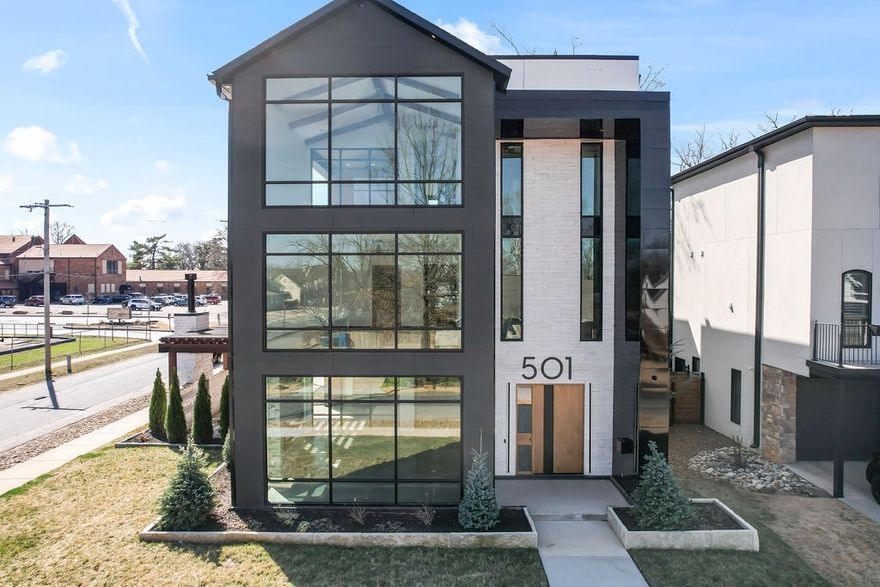 Experience luxury living in the heart of downtown Bentonville with this modern masterpiece. No expense has been spared in this stunning home.  This custom designed home features an open floor plan and an abundance of natural light from floor to ceiling glass including 37 feet of vertical clerestory windows. Situated on a corner lot with professional landscaping, this home is just steps away from Bentonville Square, Crystal Bridges Museum, and scenic bike trails. Other features include a floating staircase with hickory treads spiraling around 3 floor elevator, a four-inch walnut pivot door, Chef’s kitchen outfitted with exquisite materials, Dacor appliances, wine tower, hidden fridge and freezer, Bosch coffee station and a full prep kitchen. The luxurious owner’s suite offers a private full floor retreat with dedicated laundry, soaking tub, and a hot sauna and steam room. Additionally, the property includes a full garage house with two bedrooms, two baths, a living area, and an additional outdoor living space.