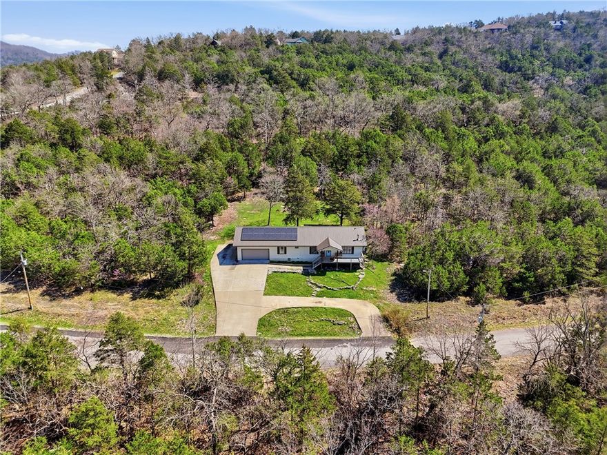 Welcome to Holiday Island! 1500+square feet, 3 bed, 2 bath, One Level home, sitting on a 1/2 acre.  AC system installed in 2020.  New metal roof and gutters in 2024. Solar Panel system for more efficient utility bills.  This home offers a friendly floor plan, along with an attached 2-car garage. Two Driveways allows plenty of space for multiple vehicles.  Backyard is beautiful and open, with a firepit! Allowing for lots of fun time!  Minutes from the community pool, marina, lake and golf courses! And of course, Eureka Springs!