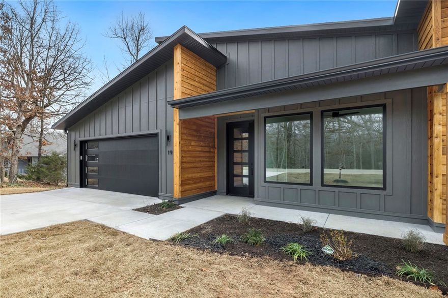 Contemporary new-construction in Bella Vista — a 2 bed, 2 bath plus dedicated office in an amenity-rich community of lakes, trails and golf. This home stands apart with oak hardwoods throughout, oversized windows bathing rooms in natural light, and designer details at every turn. The chef’s kitchen features a full tiled backsplash, quartz counters with custom oak accent and waterfall island. Oak-trimmed accent beams in the living area and owners’ suite add warmth; full tiled showers and a striking tiled accent wall with gas log fireplace and oak mantel deliver luxe finishes. Additional upgrades include a gorgeous front entry door, upgraded modern garage door with sidelight glass, covered back deck, and a full mudroom with custom cubbies for effortless organization. Move-in ready and distinctly elevated.